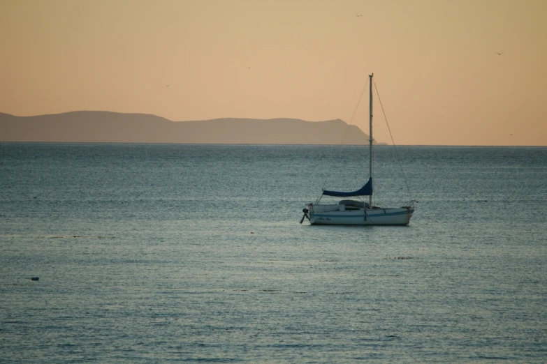 a lone white boat in the middle of blue water