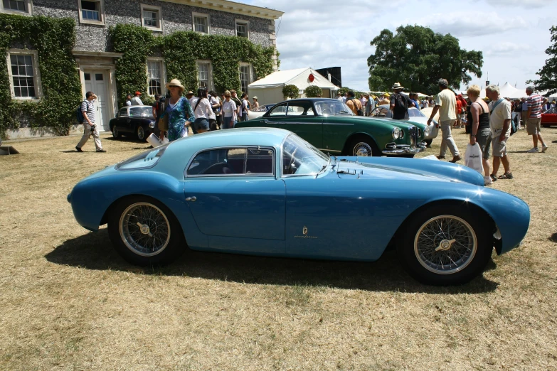 two blue cars on display in a building yard