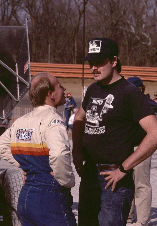 two men standing near a truck talking to one another