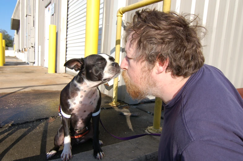 a man is kissing his dog outside of a building