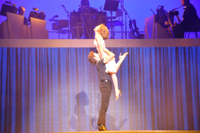 a man holds the arm and body of a woman on stage