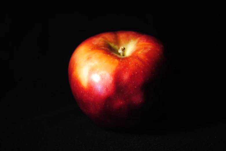 an apple that is on top of a black surface