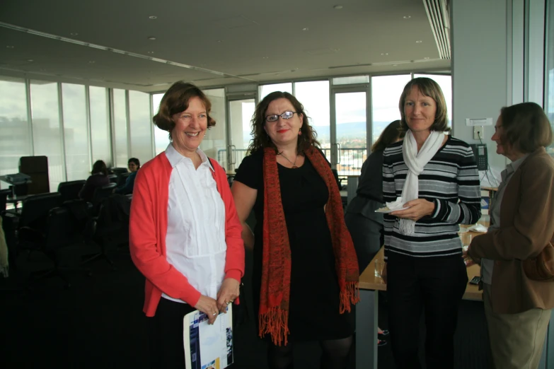 four women with large glasses standing by desks