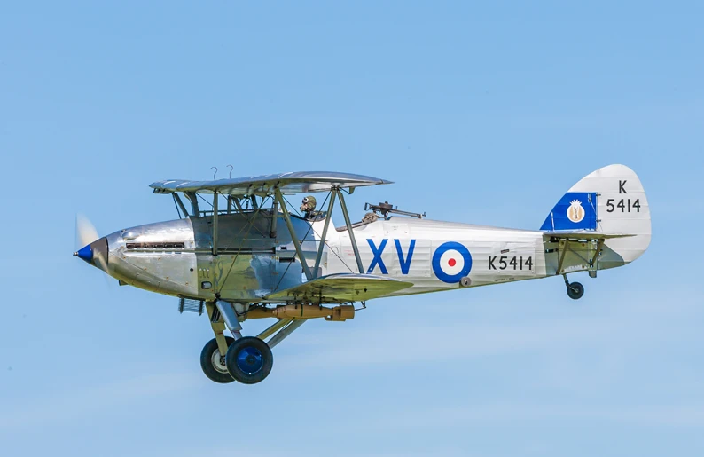 an old airplane flying in a blue sky