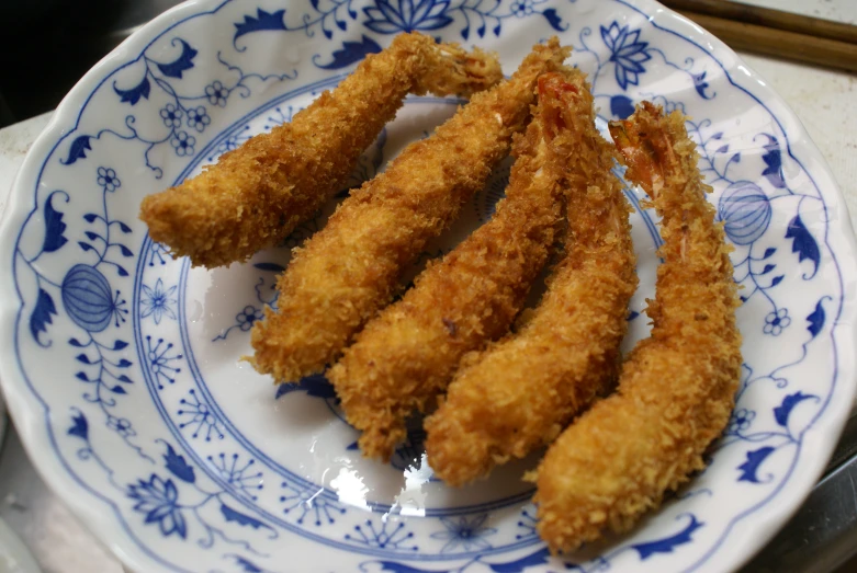 fried vegetable sticks on plate near chopsticks on table