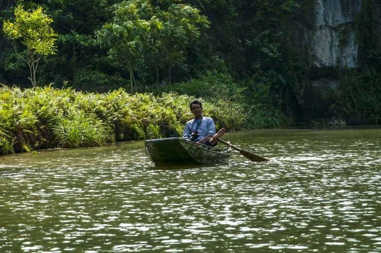 the man is rowing the small boat in the river