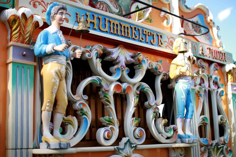 statues are pictured above the colorful facade of a carnival attraction