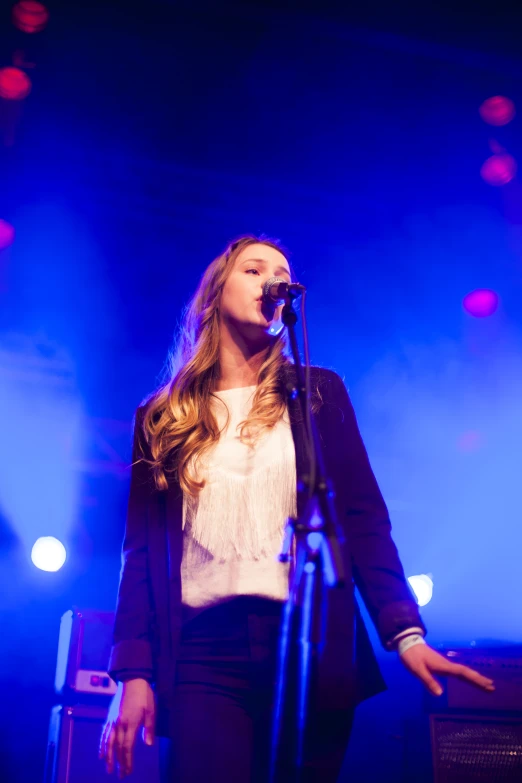 a girl singing at a concert with her microphone on