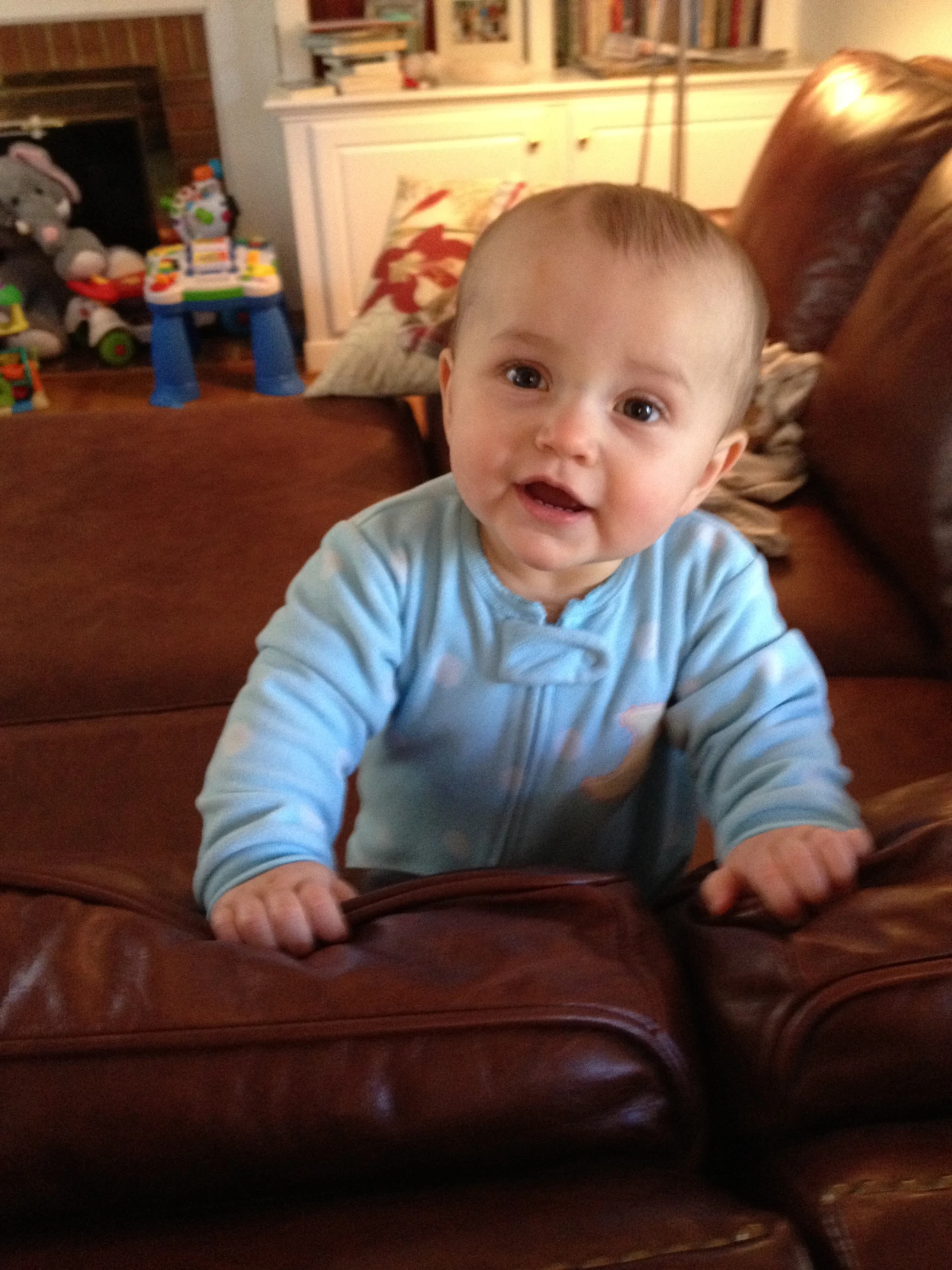 the baby is sitting on top of the leather sofa