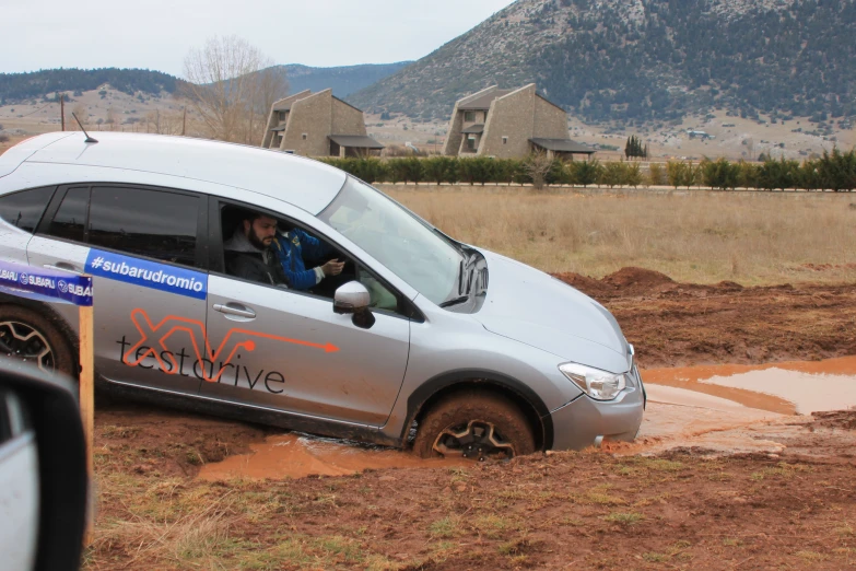 a small silver van with a graffiti sign near a farm