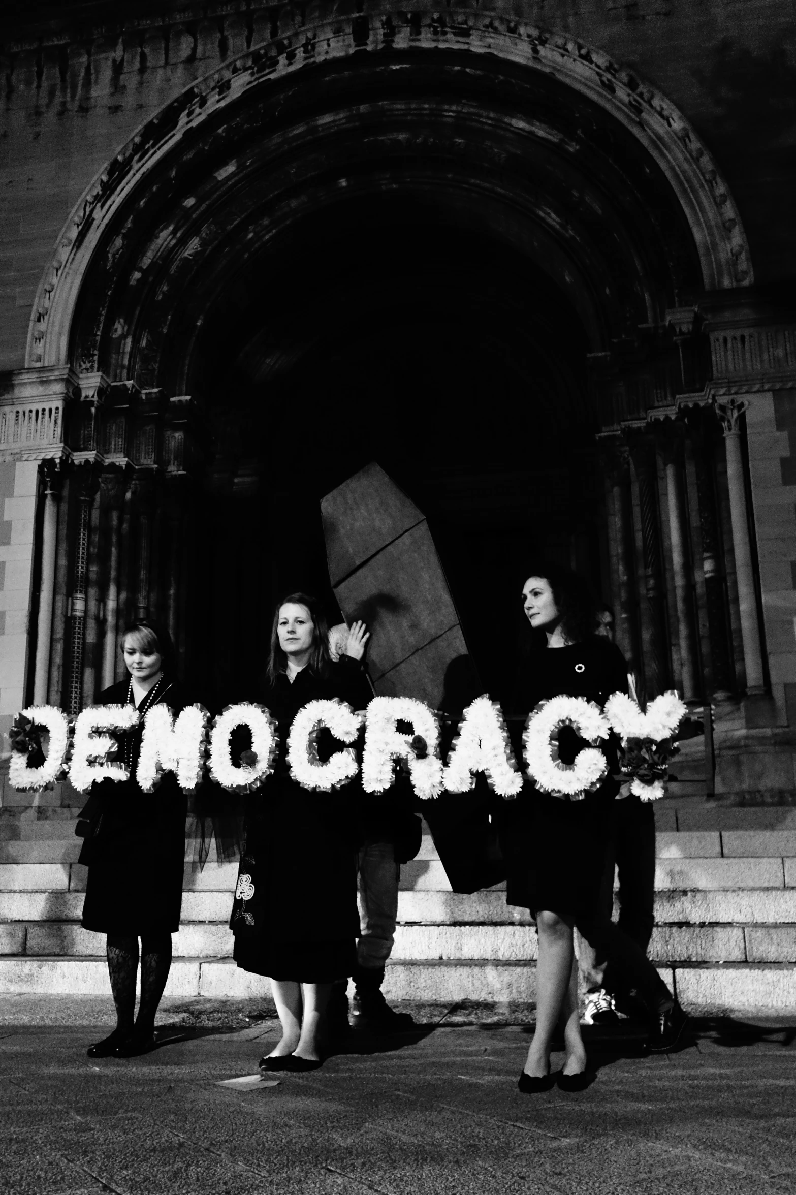 group of people holding a sign that reads democracy