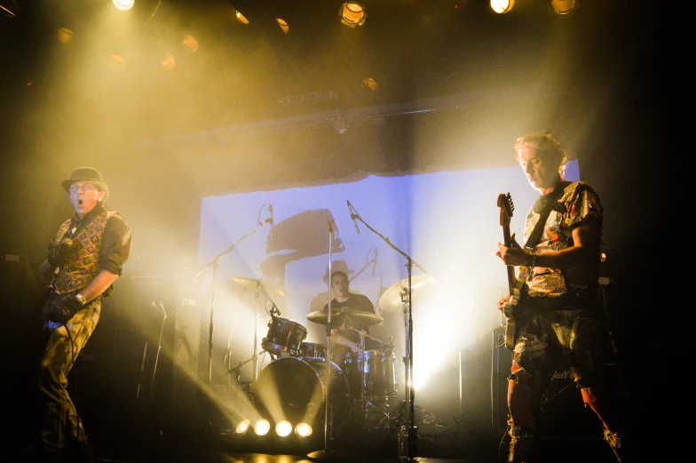 three men playing instruments on stage during night