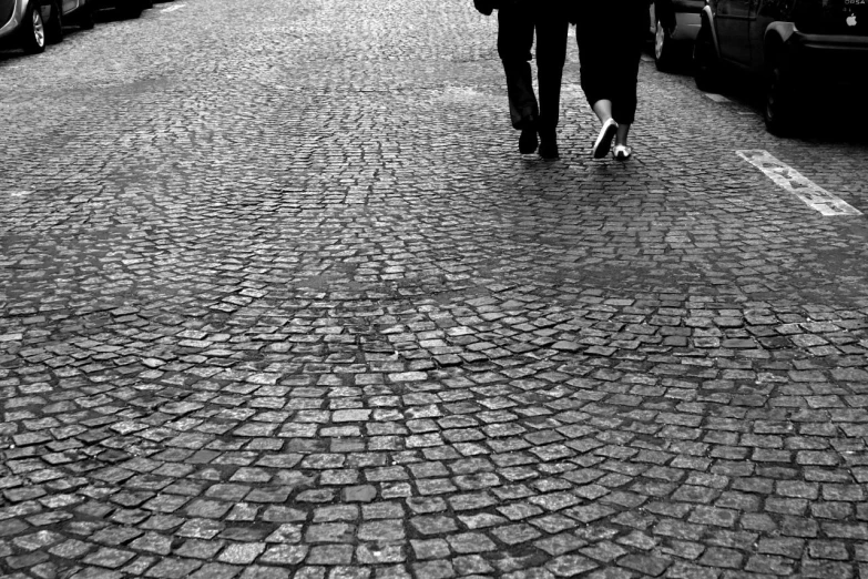 a man and woman are walking down a brick road