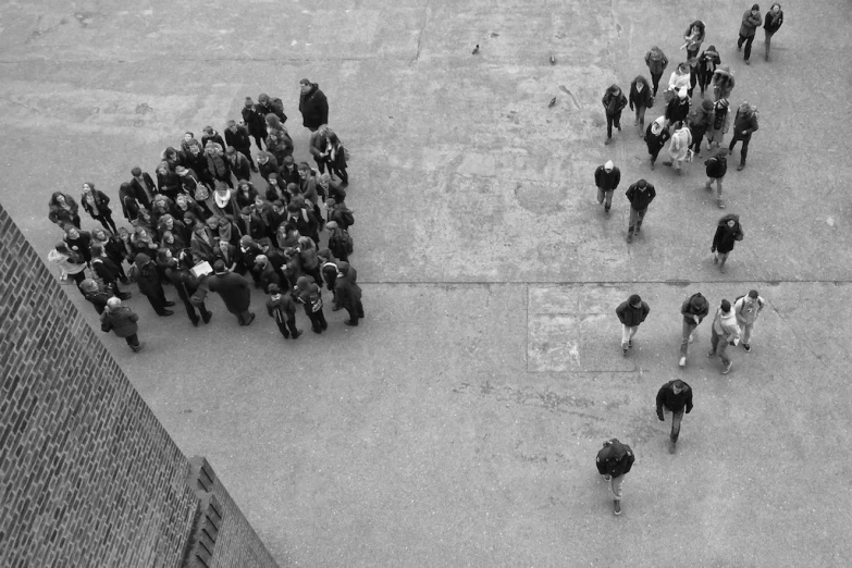 an aerial view of people and horses standing on the sidewalk