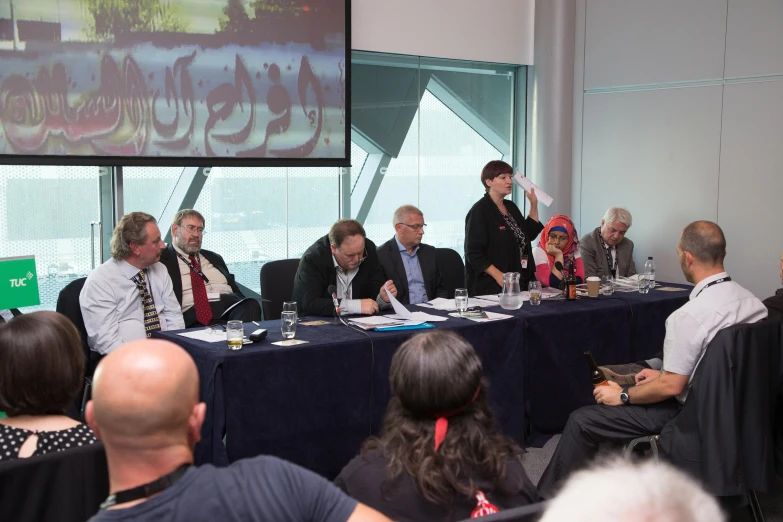 group of people sitting at a table listening to a presentation