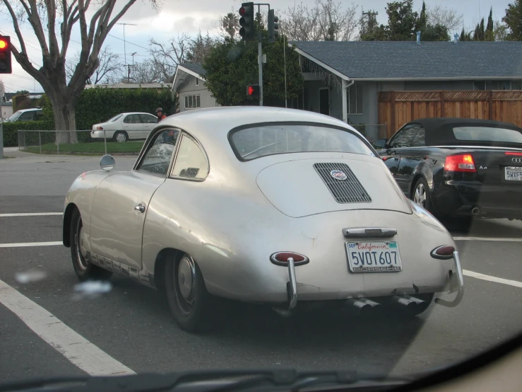 an old silver sports car in front of cars