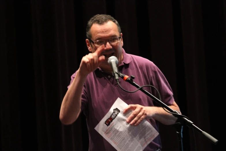 a man wearing glasses speaks into a microphone