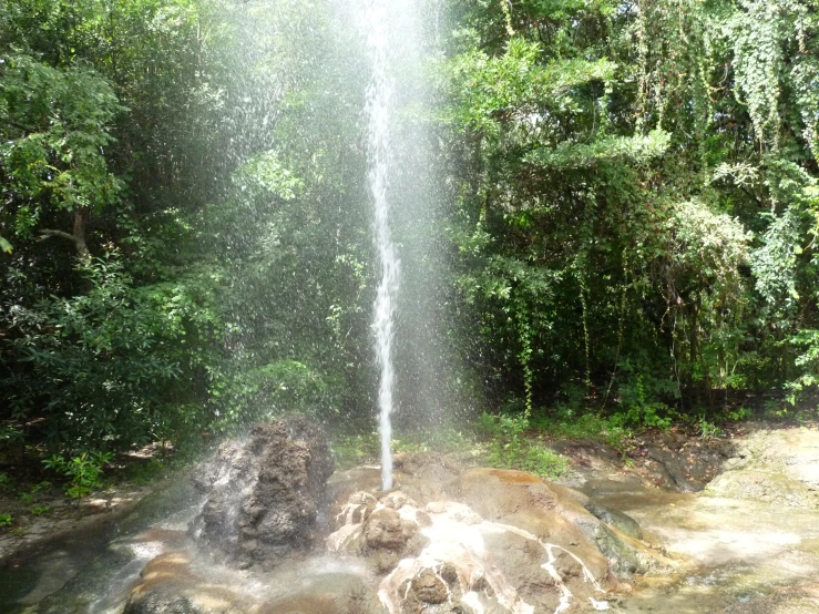 a waterfall is spouting over a rocky stream in the jungle