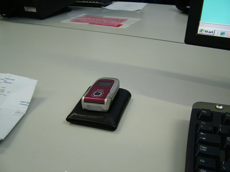 a cell phone sits on a stand with a keyboard nearby