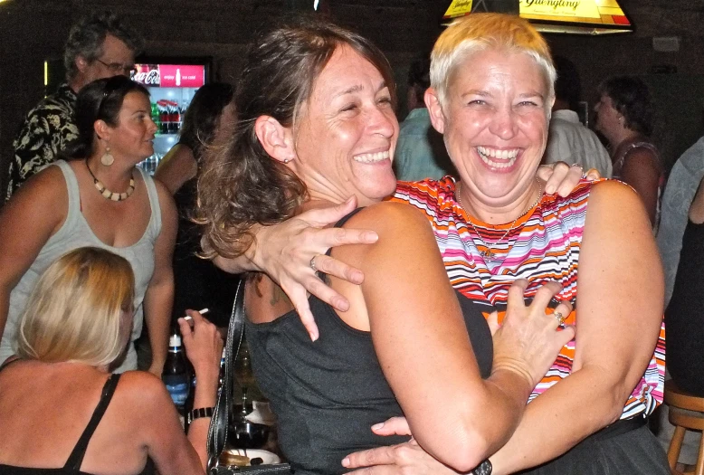 two women hugging while having a party at the same time