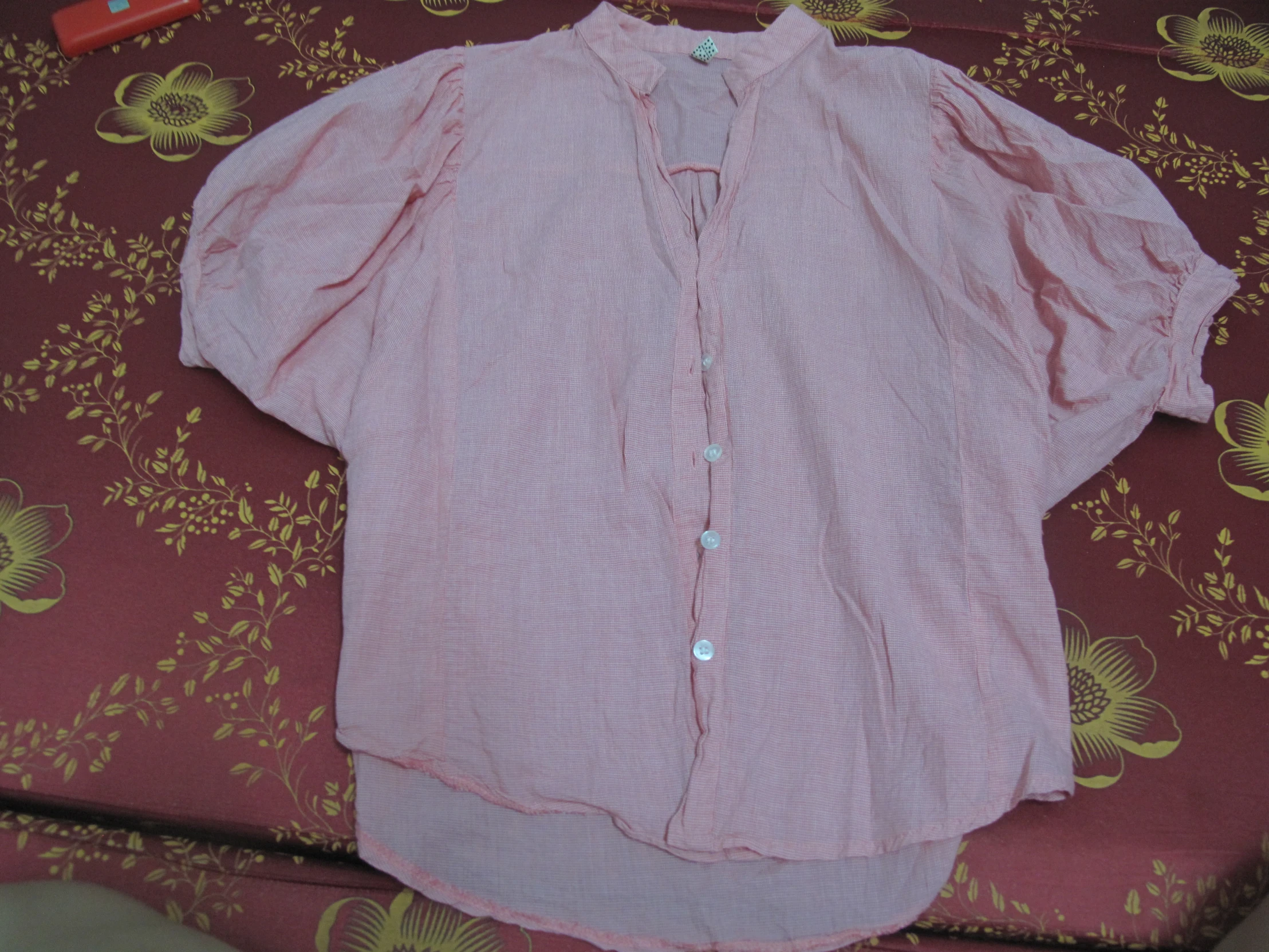 a pink shirt and red pen lying on top of a red cloth