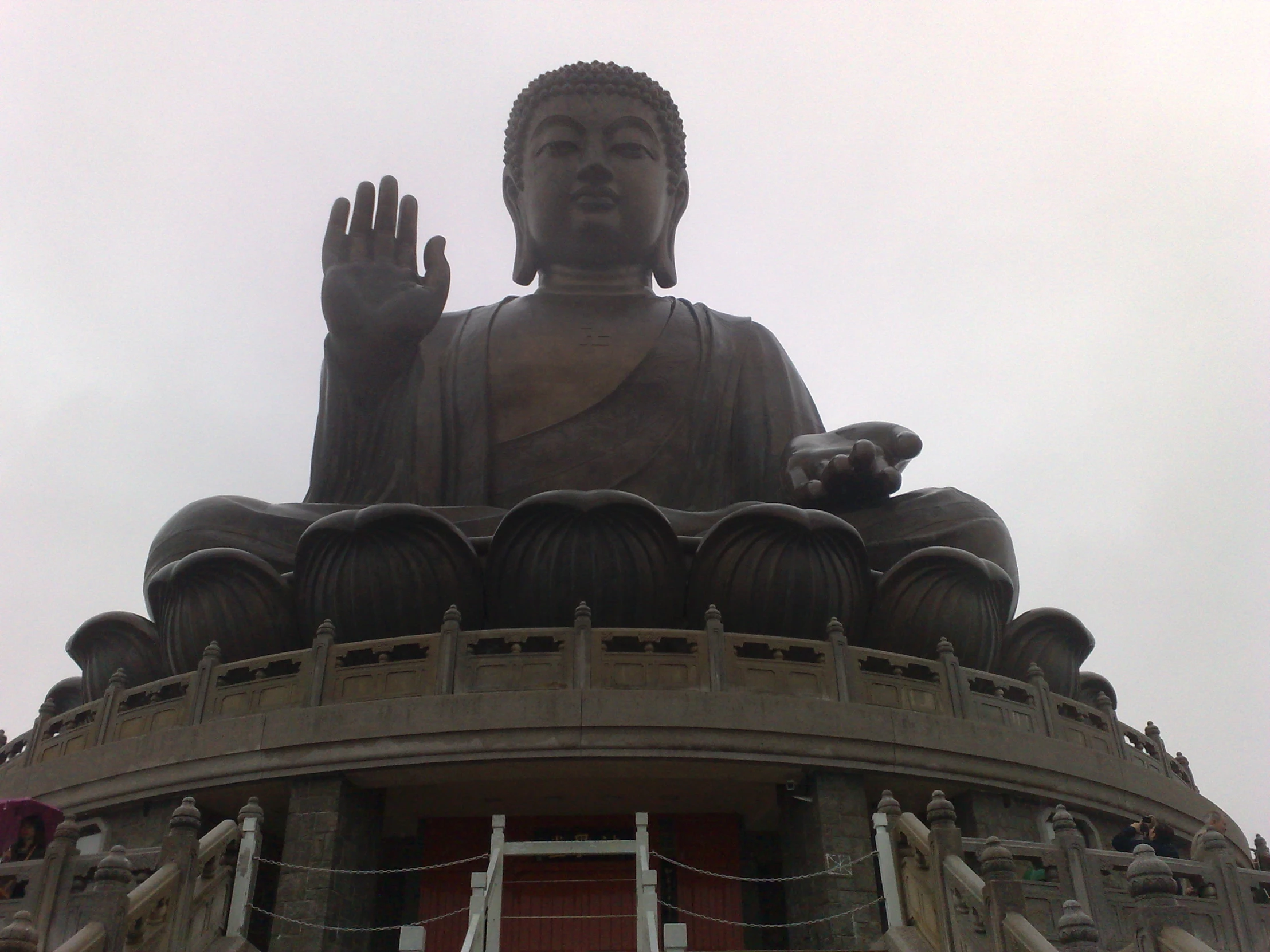 a large buddha statue next to stairs and fence