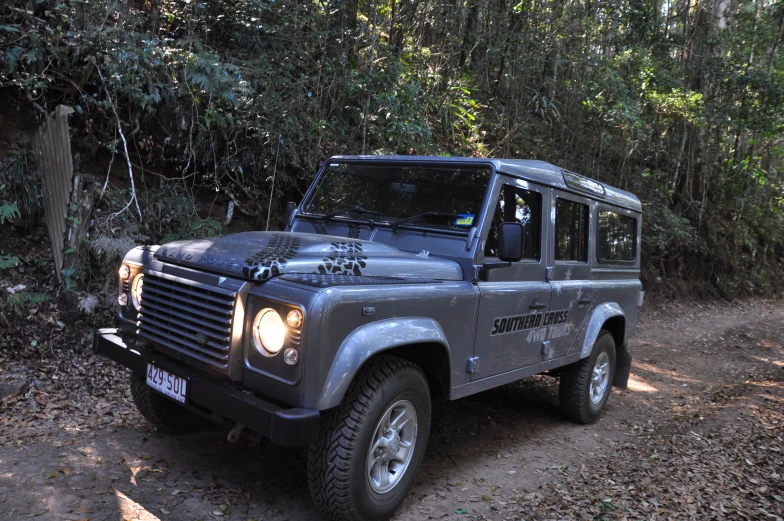 a gray jeep is parked in front of trees