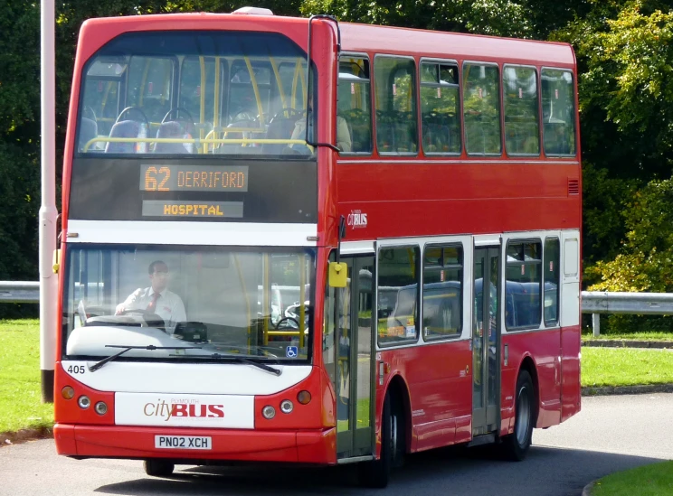 a red double decker bus is shown driving down the street