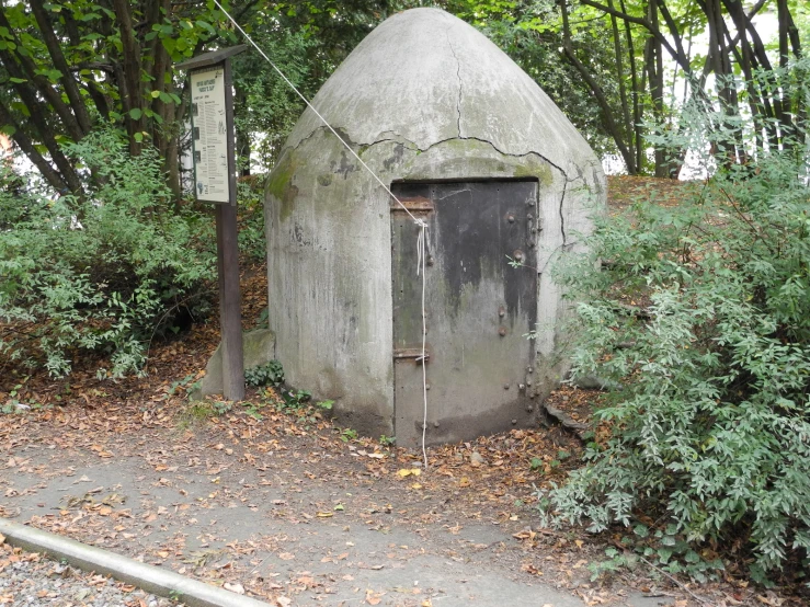 an outhouse sitting next to a bush with the door open