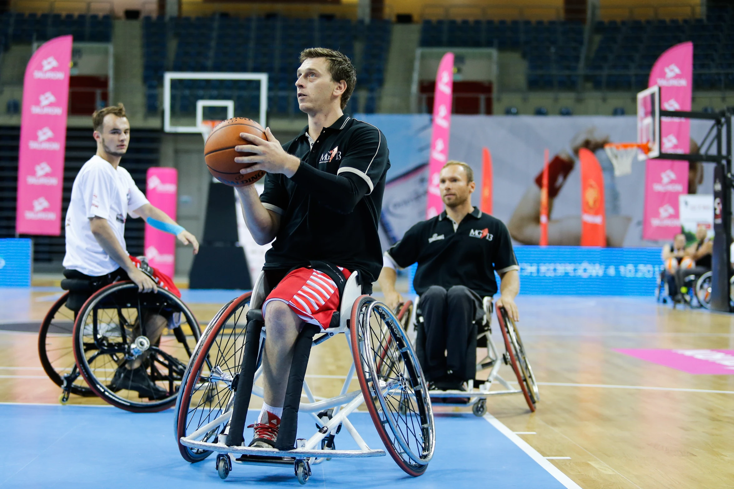 two wheelchair basketball players practice with the referee in a gym