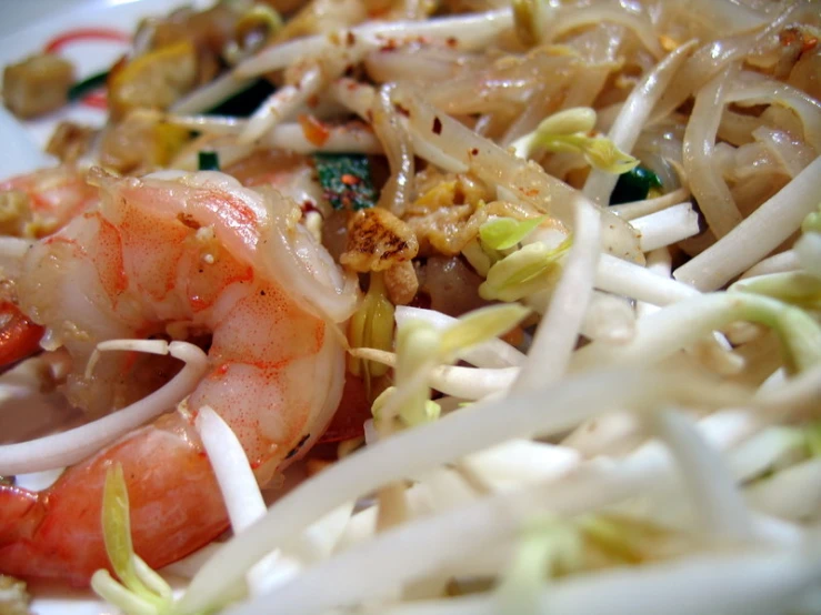 there are shrimp, noodles, carrots and other foods in the plate