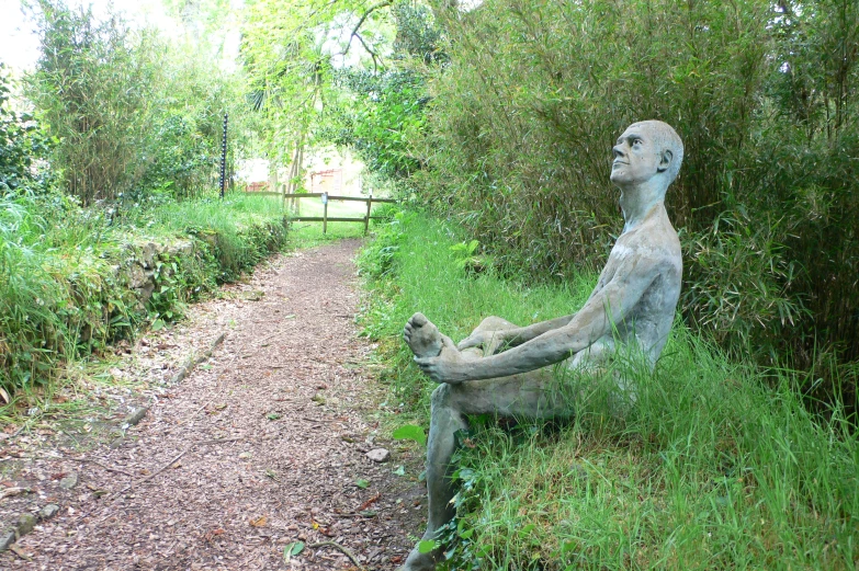 there is a statue sitting on the ground next to a pathway