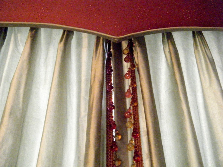 the curtains on the bed have many beaded ribbons hanging from them