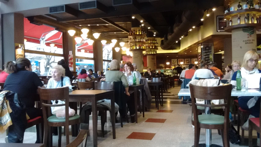 several people are sitting at tables in the dining area of a restaurant