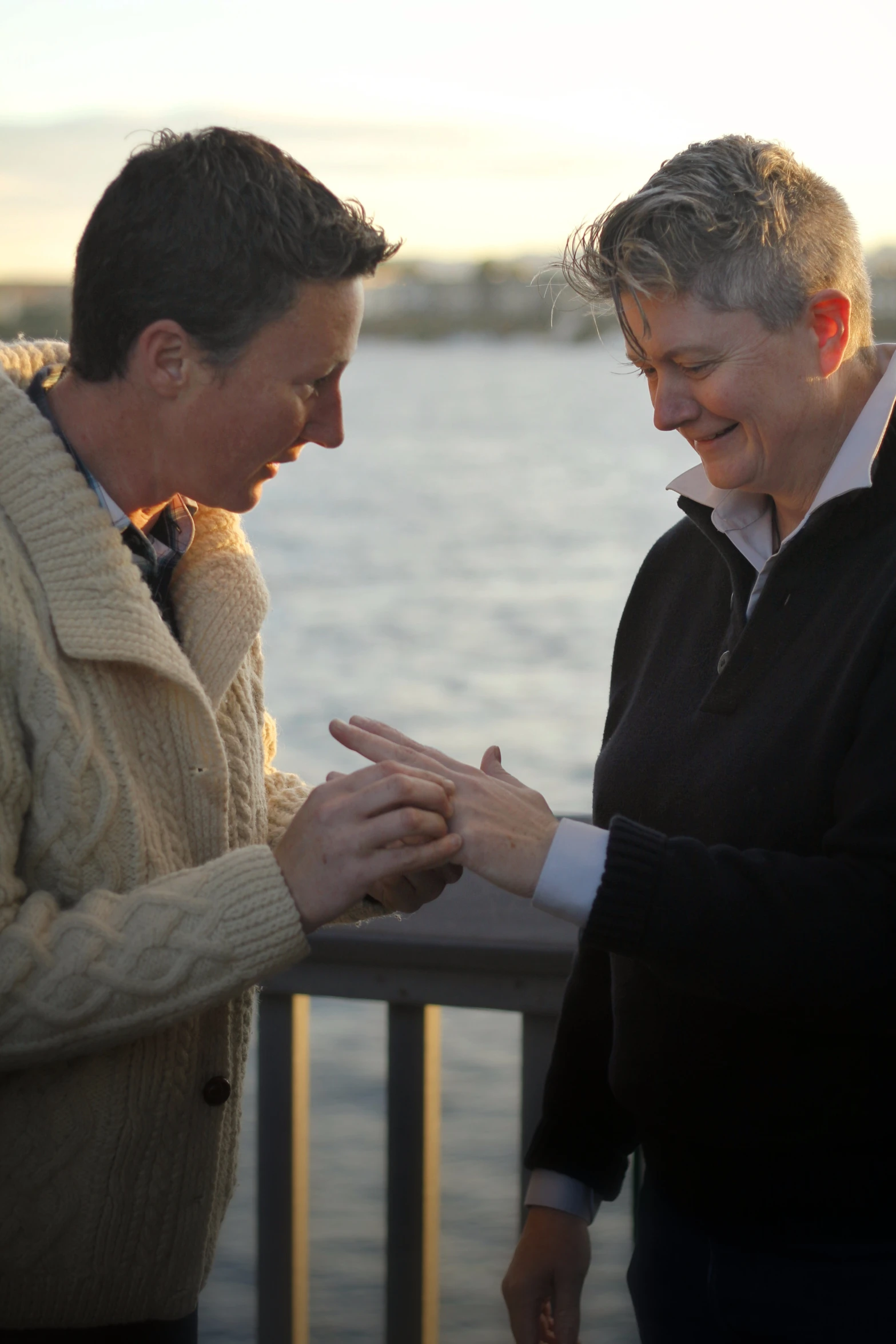 two people are greeting each other by standing on the pier