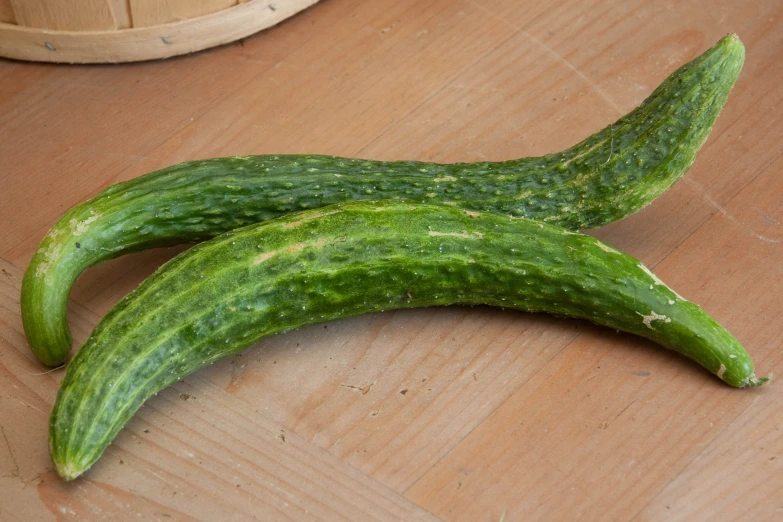 two large green cucumbers on top of a wooden surface