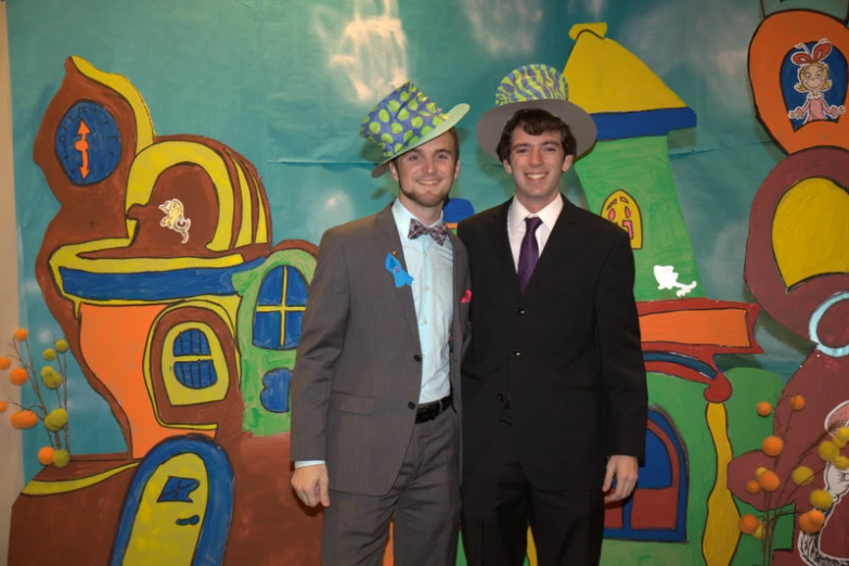 two guys in front of a large wall decorated with cartoon scenes