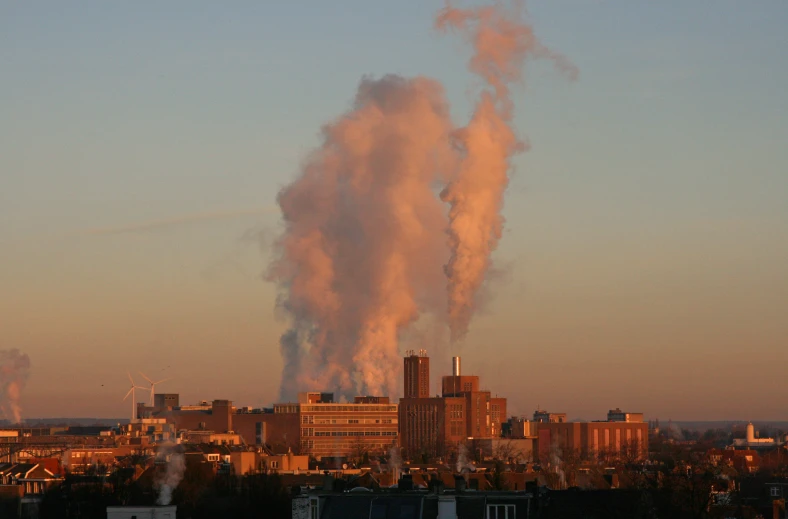 smoke coming out the chimneys from some tall buildings