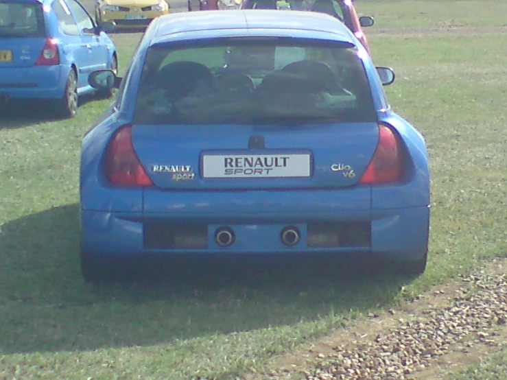 the front of a blue car parked in a grassy area