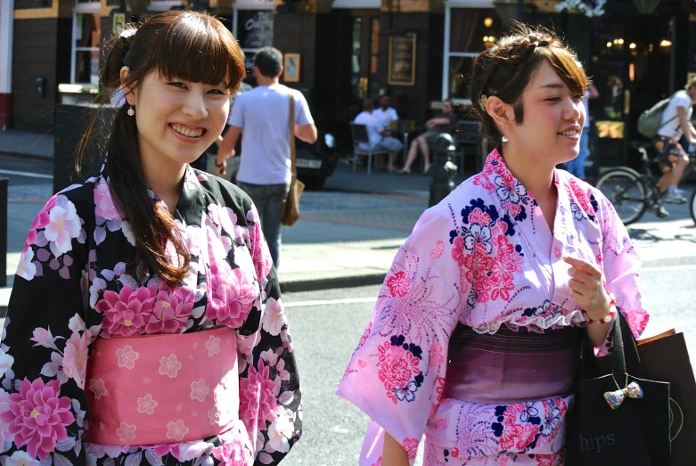 two women in a japanese traditional outfit smile at the camera