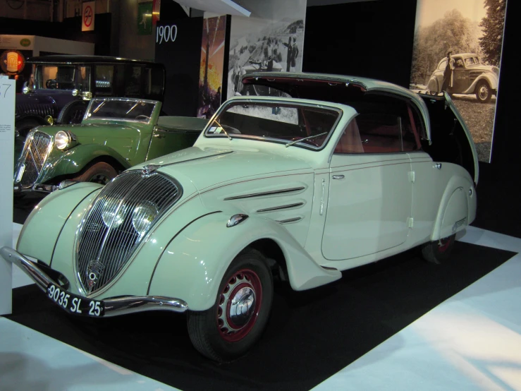 an old car on display with other cars in the background