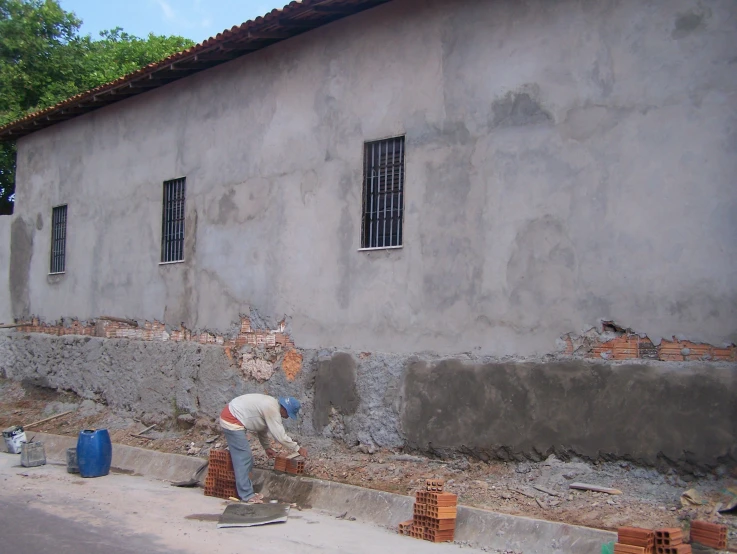 someone leaning on the side of a building with bricks