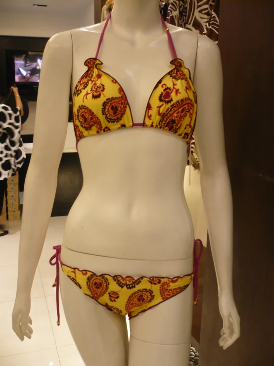 a white mannequin with a  yellow and red swim suit on display