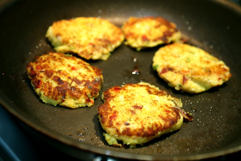 four crab cakes in a pan on a stove
