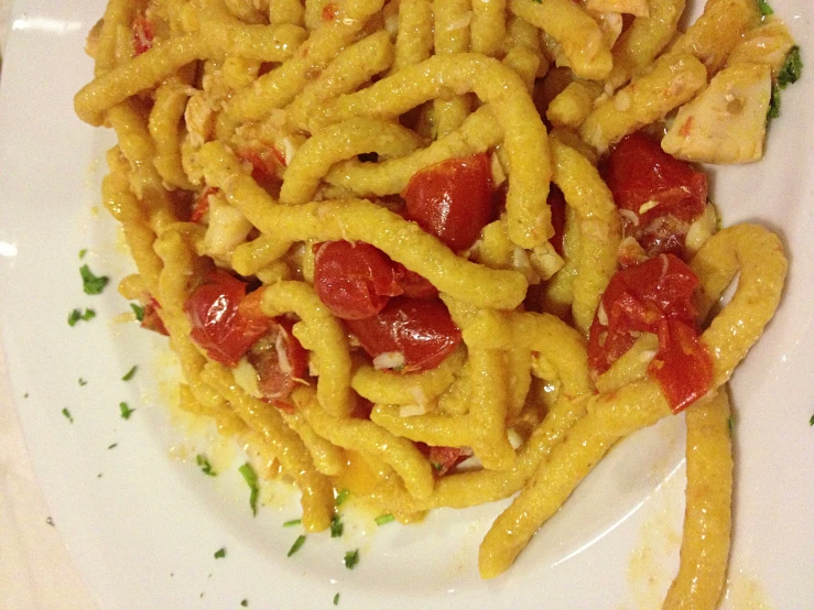 a white plate topped with chicken spaghetti and tomatoes