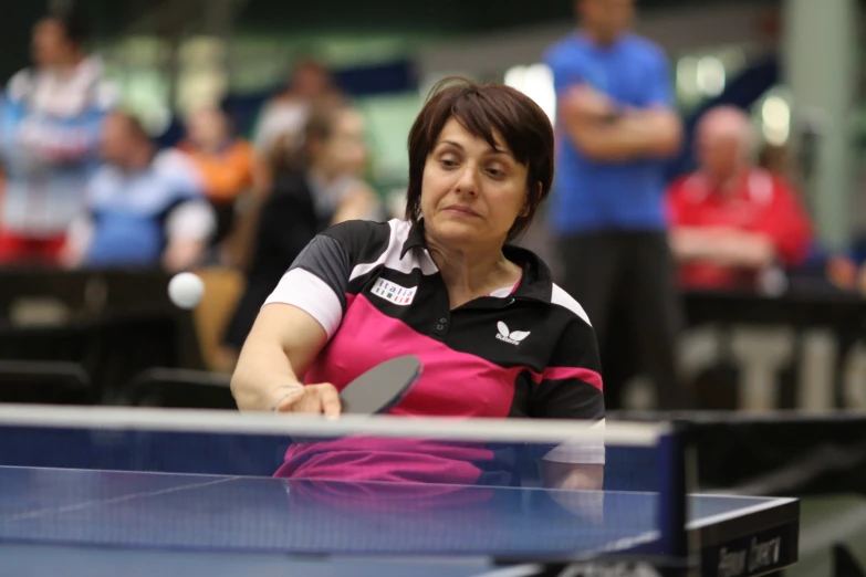 a woman holding a racket looks down at the tennis ball