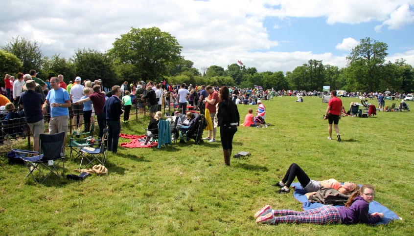 a large crowd of people on grass with a man laying on the ground