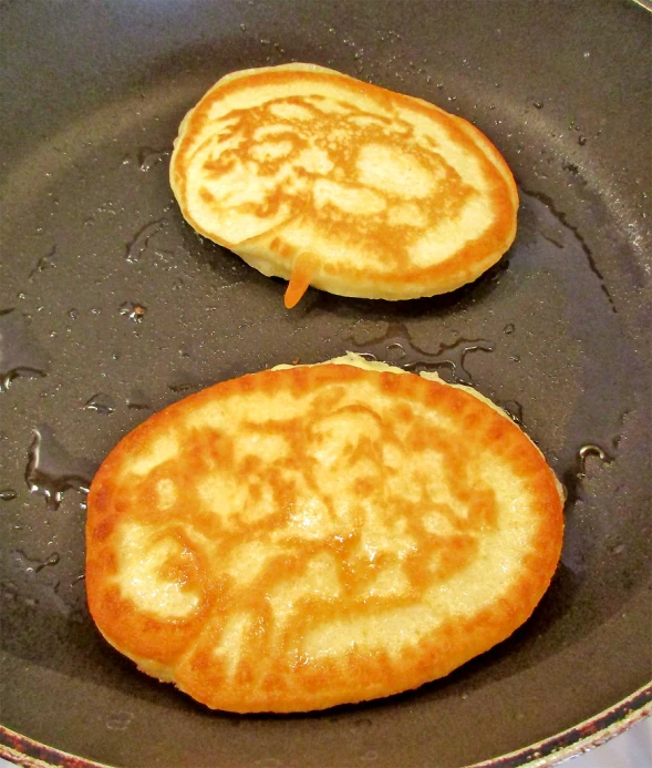 some pancakes cooking on a frying pan