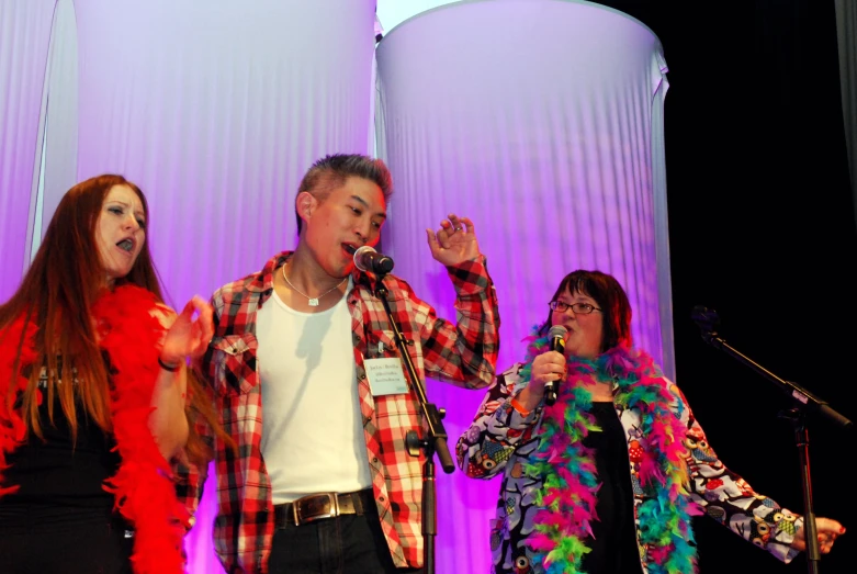 a man and two women sing with a microphone