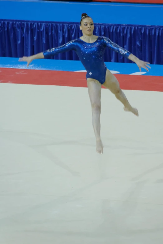 a woman is performing a move on a skate rink